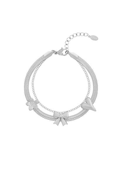 Silver stainless steel charm bracelet with bow, heart, and flower charms on white background