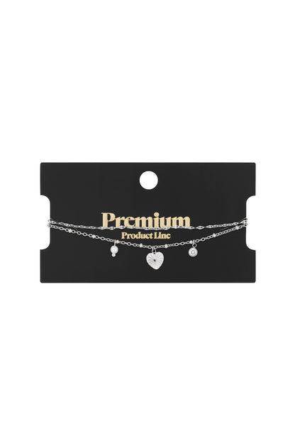 Silver-tone double-strand bracelet with heart, pearl, and crystal charms on a black "Premium Product Line" card.