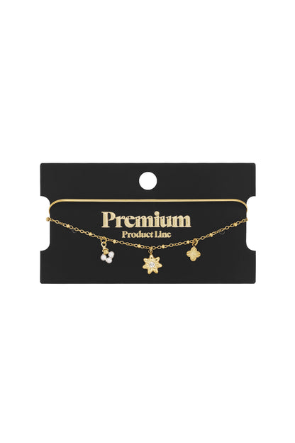 Gold layered floral charm bracelet on black packaging card with Premium Product Line label