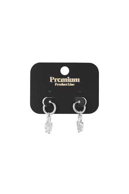 Silver clover charm hoop earrings displayed on black Premium Product Line card