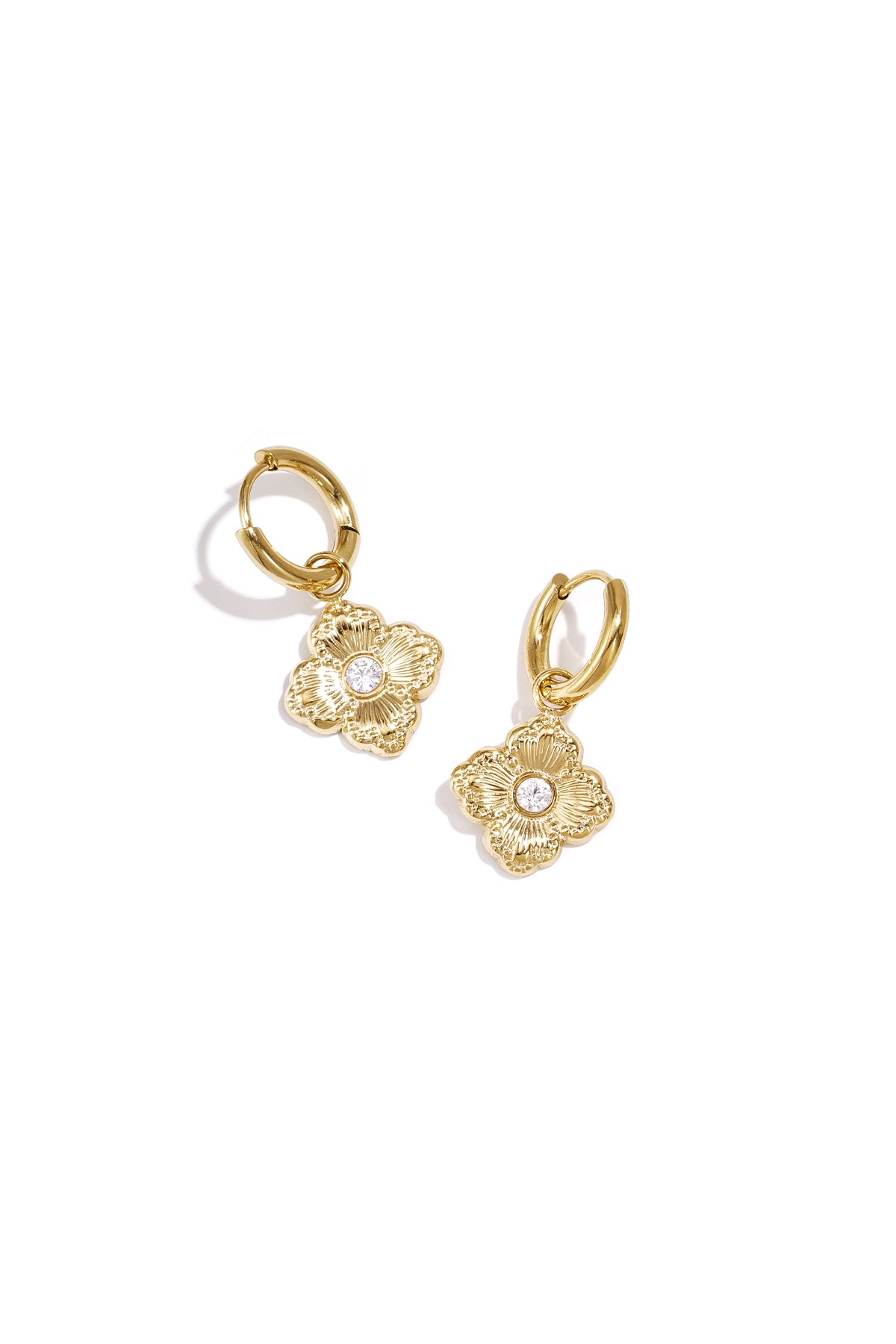 Pair of gold-tone clover charm drop earrings with zircon stones on white background