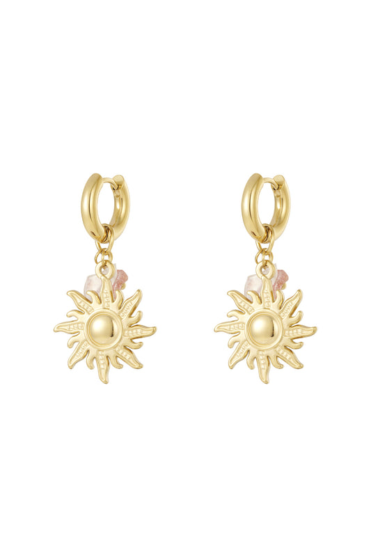 Pair of gold sun charm drop earrings with pink bead accents displayed on white background