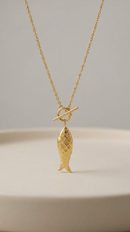 Gold Catching Vibes necklace featuring a detailed fish pendant hanging from a minimalist toggle clasp.