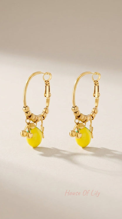 Gold hoop earrings featuring beaded detailing with yellow lemon and small gold cherry charms.