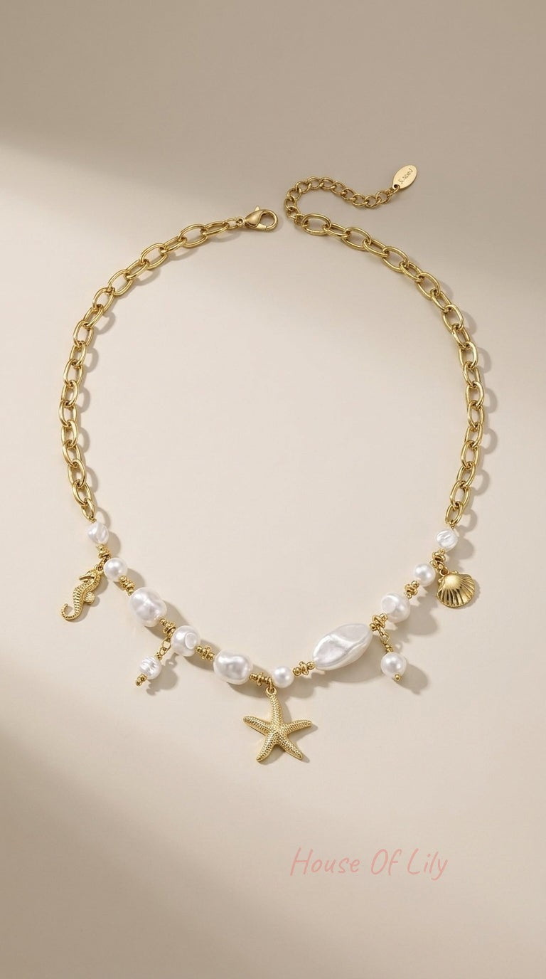 Gold chain necklace with irregular pearls and ocean charms: a starfish, seahorse, and seashell.