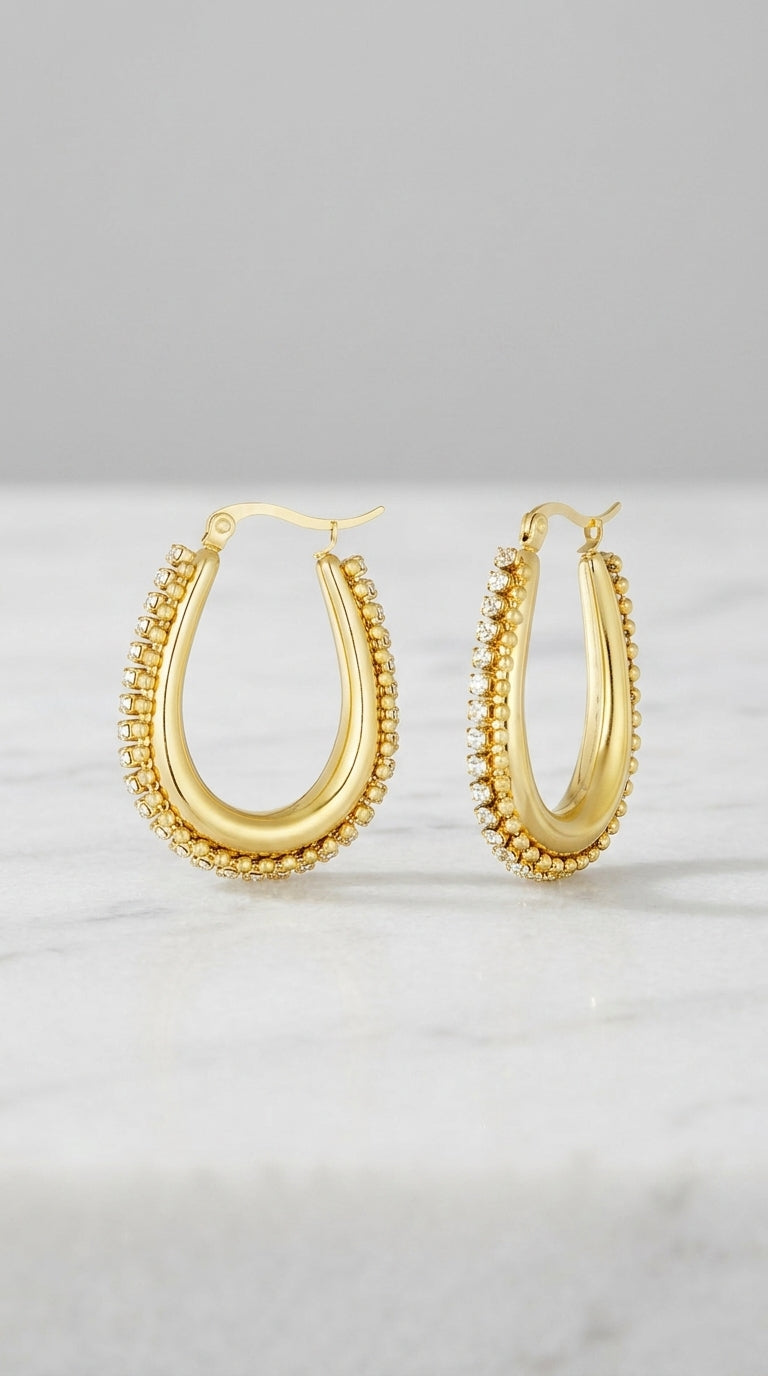 Drip Drop Glow gold hoop earrings, U-shaped with a central smooth band bordered by shimmering beaded crystal edges.