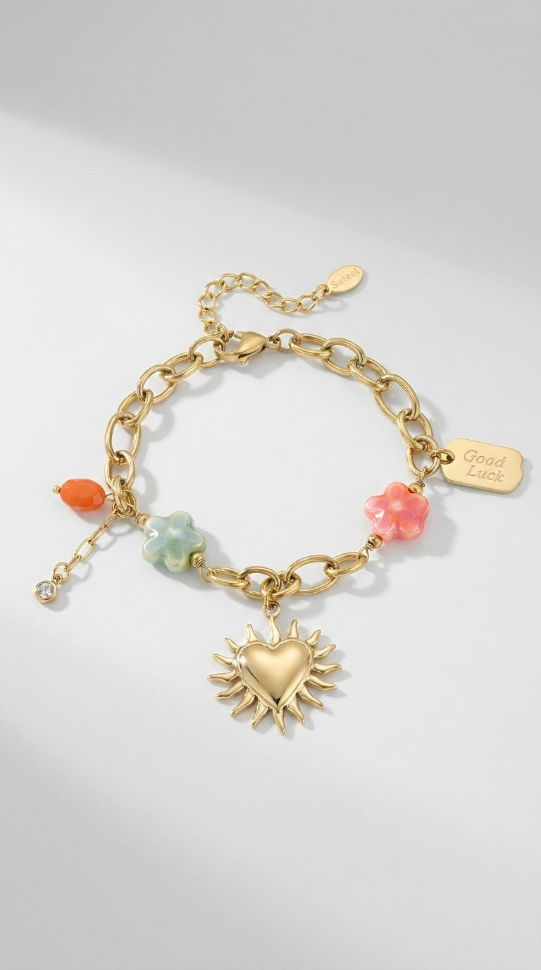 Charm Era Unlocked gold-tone chain bracelet featuring a sun-heart pendant, colorful flower charms, and "Good Luck" tag.