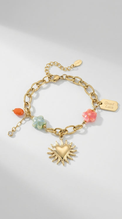 Charm Era Unlocked gold-tone chain bracelet featuring a sun-heart pendant, colorful flower charms, and "Good Luck" tag.