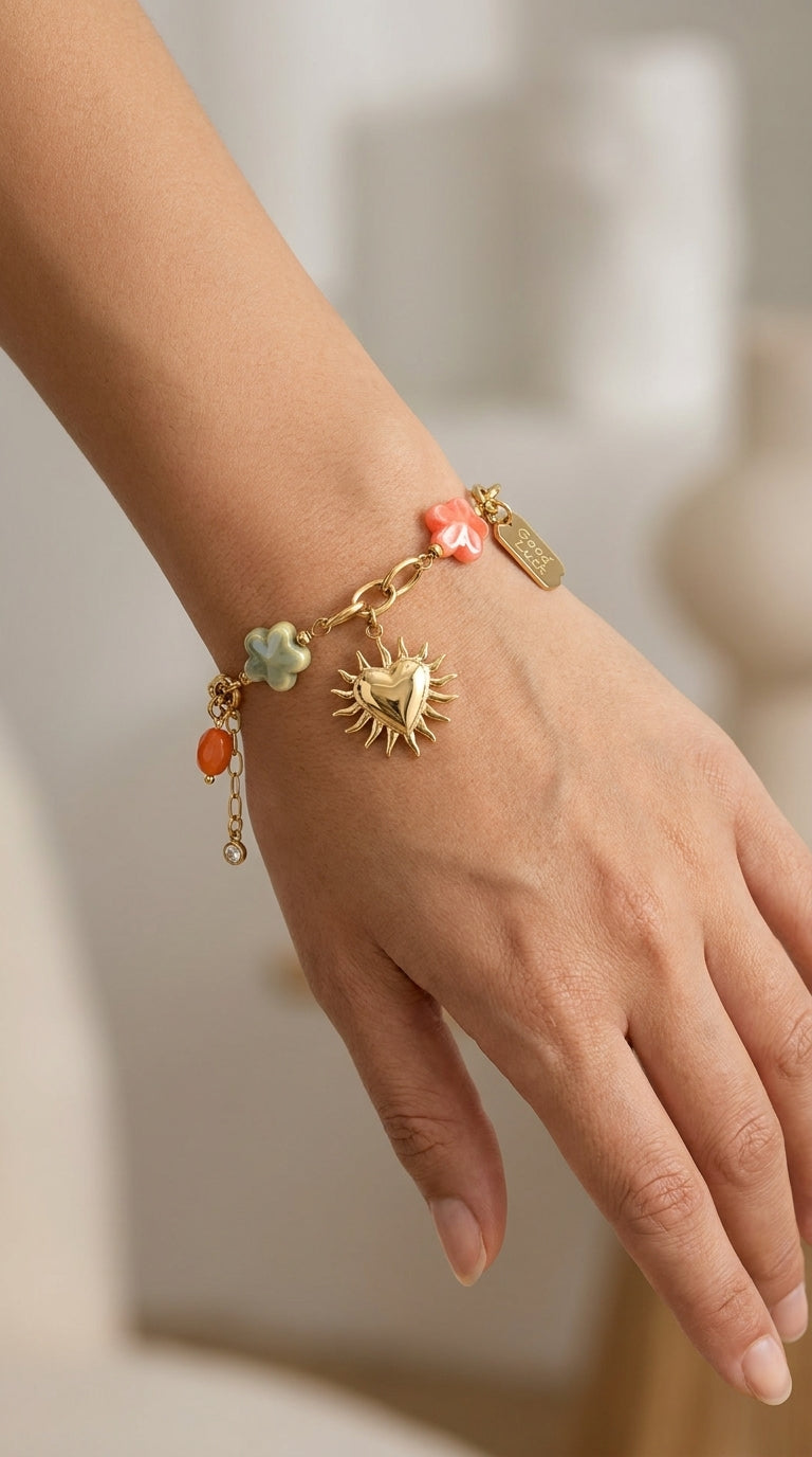 Charm Era Unlocked gold-tone link bracelet featuring a sun-heart charm, colorful flower charms, and "Good Luck" tag.
