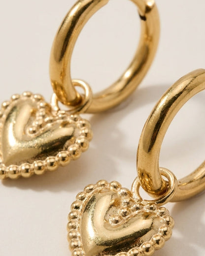 Gold hoop earrings featuring beaded-edge puffy heart charms suspended from each loop.