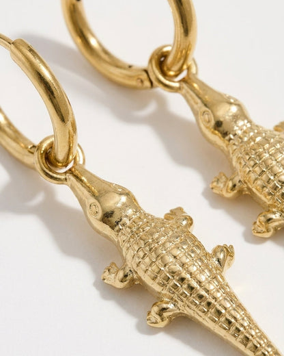 Gold-tone drop earrings featuring detailed, textured crocodile charms hanging from small hoop earrings.