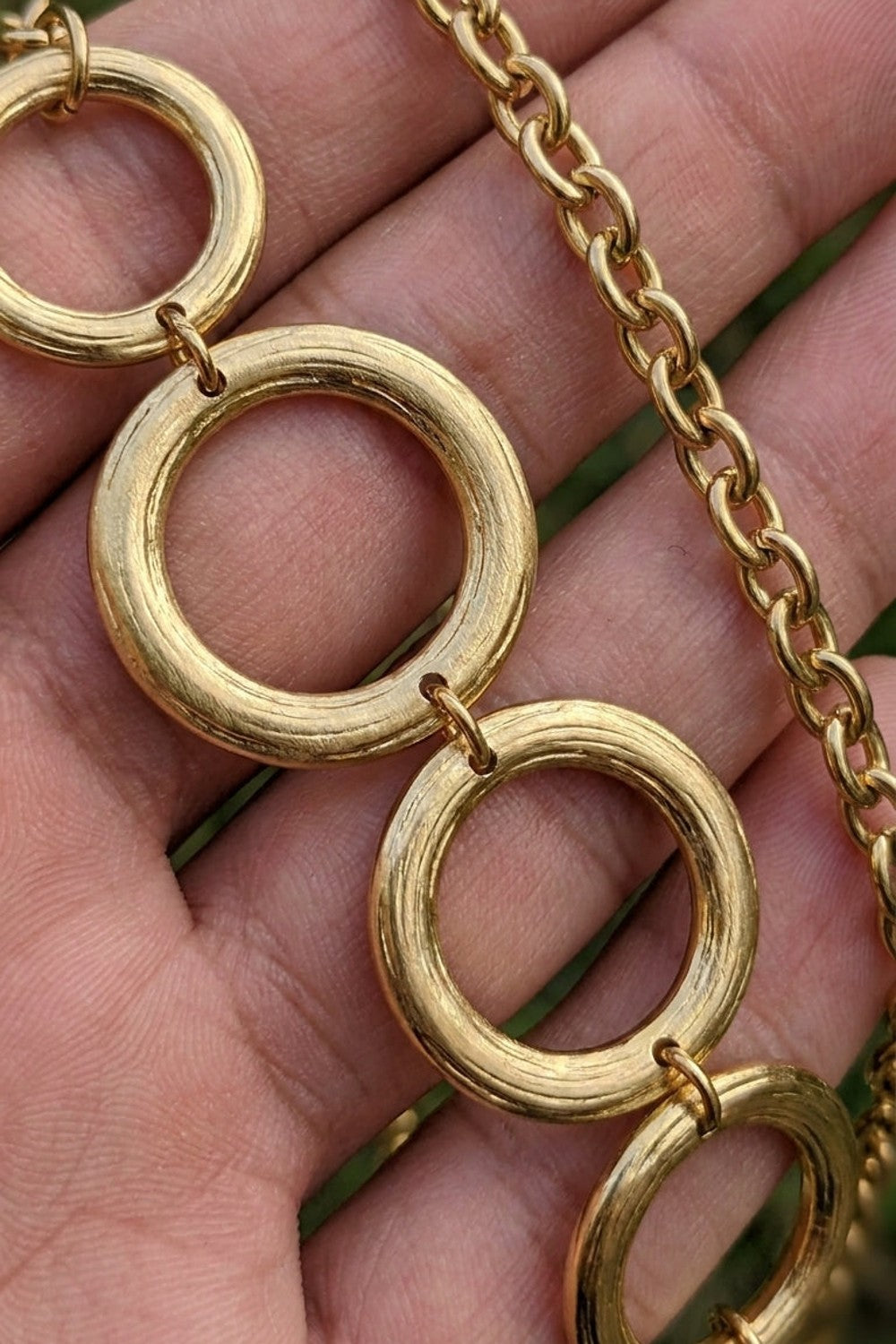 Gilded chain statement necklace featuring a series of interlocking gold-toned rings.