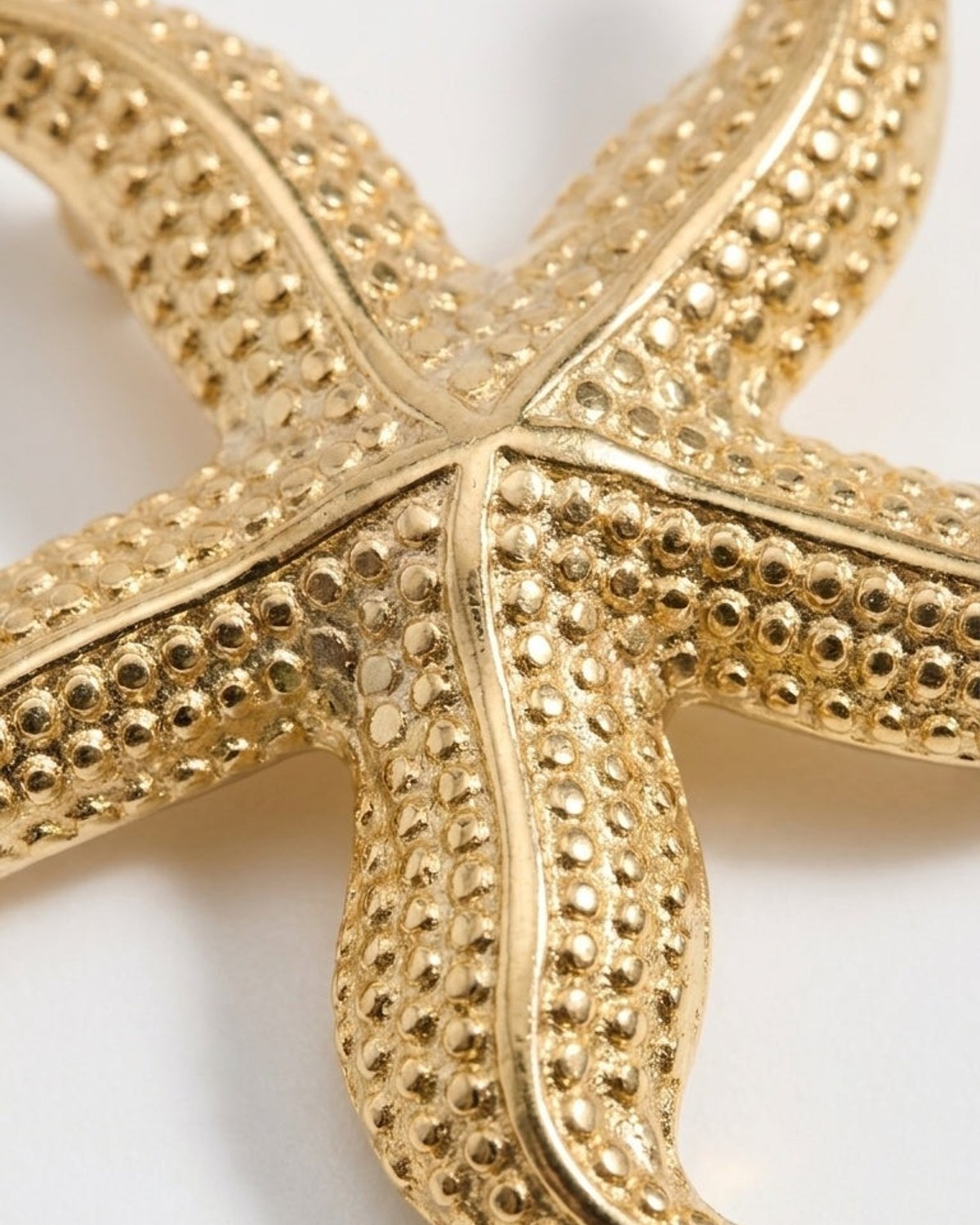 Textured gold starfish pendant on a white background.