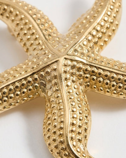 Textured gold starfish pendant on a white background.