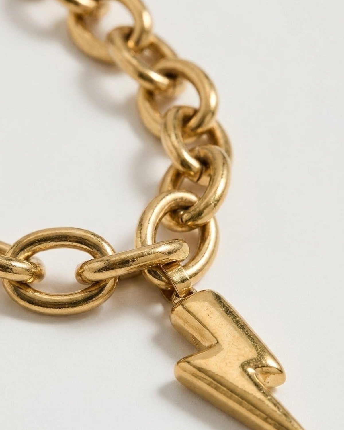Gold-toned metal chain necklace with a chunky lightning bolt pendant against a white background.