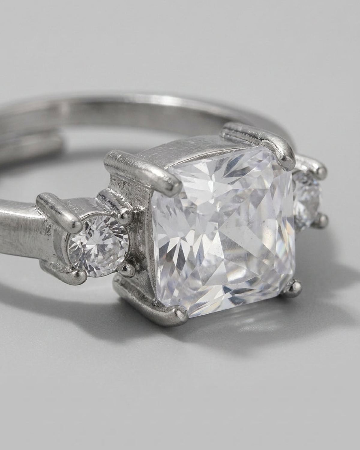 Silver-tone ring featuring a large square rhinestone flanked by smaller round rhinestones in prong settings.