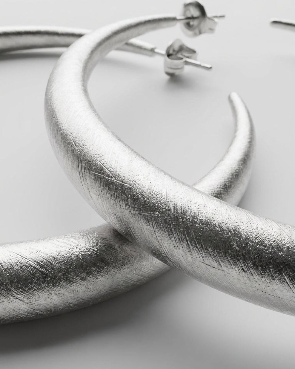 Textured silver hoop earrings with a brushed finish and post backs, in a modern, organic style.