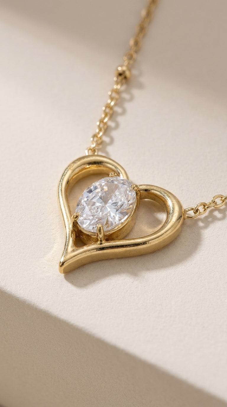 Gold-finished stainless steel necklace with a heart pendant holding a central oval gemstone on a delicate chain.