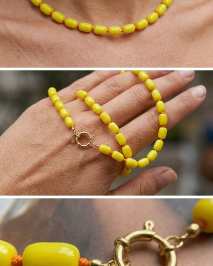 A yellow beaded necklace with chunky cylinder-shaped beads strung on orange cord and a gold clasp.
