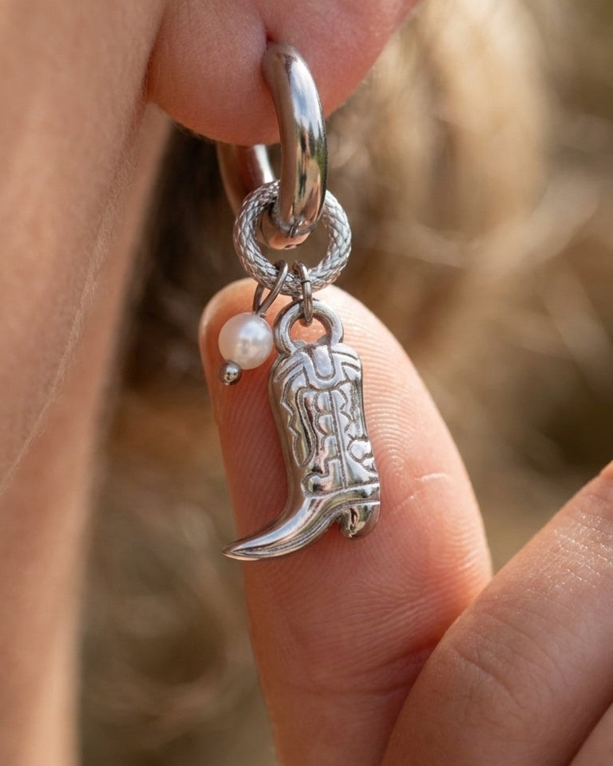 Silver Western cowgirl boot drop earring with small pearl charm on earlobe.