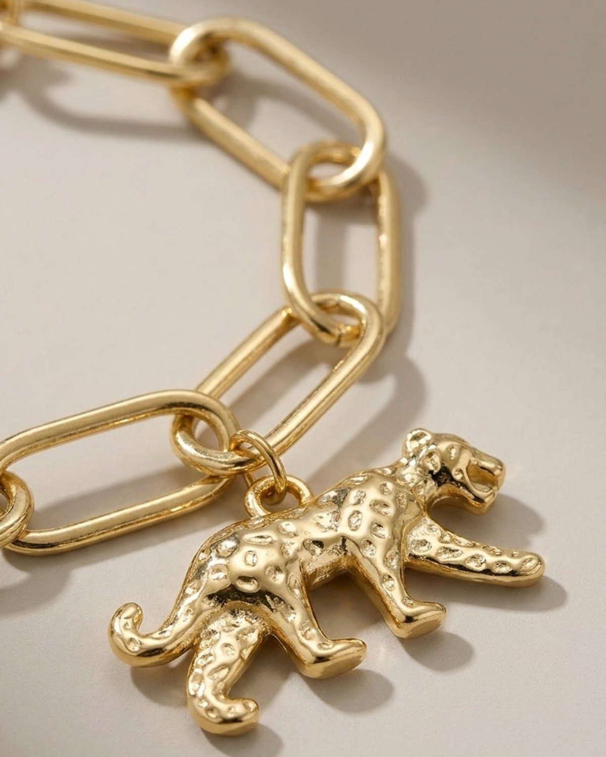 Gold paperclip-link chain bracelet featuring a textured leopard charm.