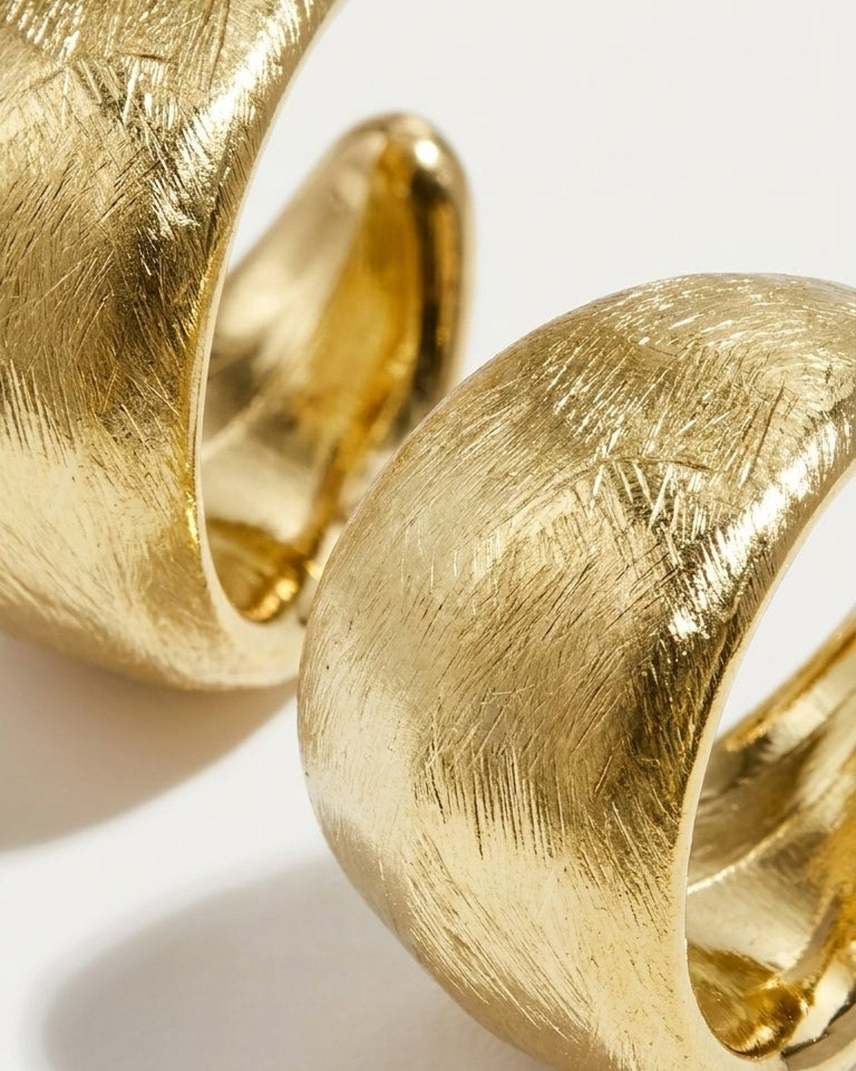 Chunky gold hoop earrings with a brushed, textured finish and polished interior.