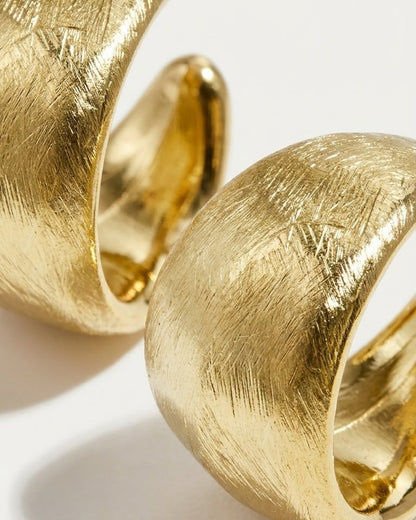 Chunky gold hoop earrings with a brushed, textured finish and polished interior.