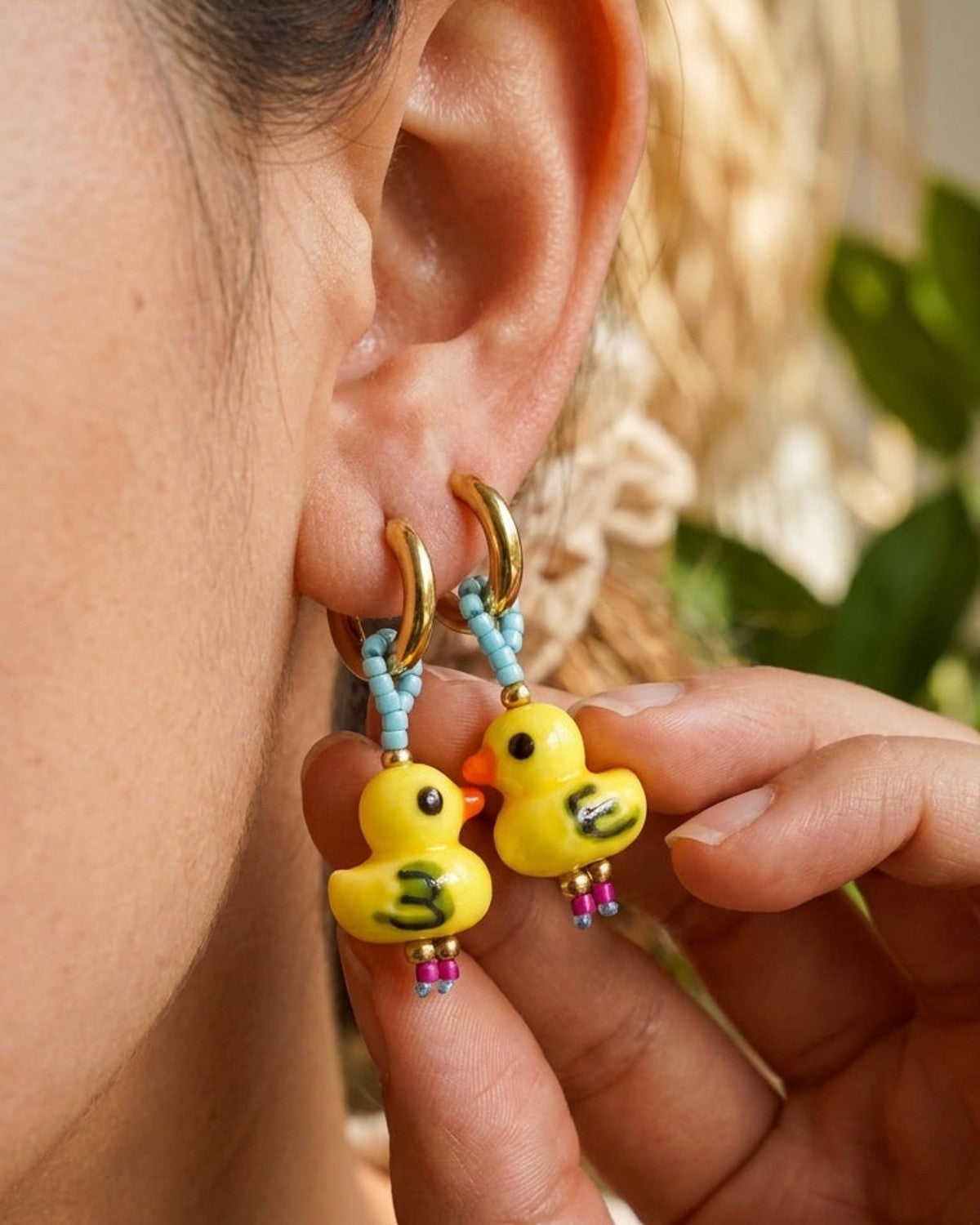 Gold hoop earrings featuring yellow duck charms suspended by light blue beaded strands.