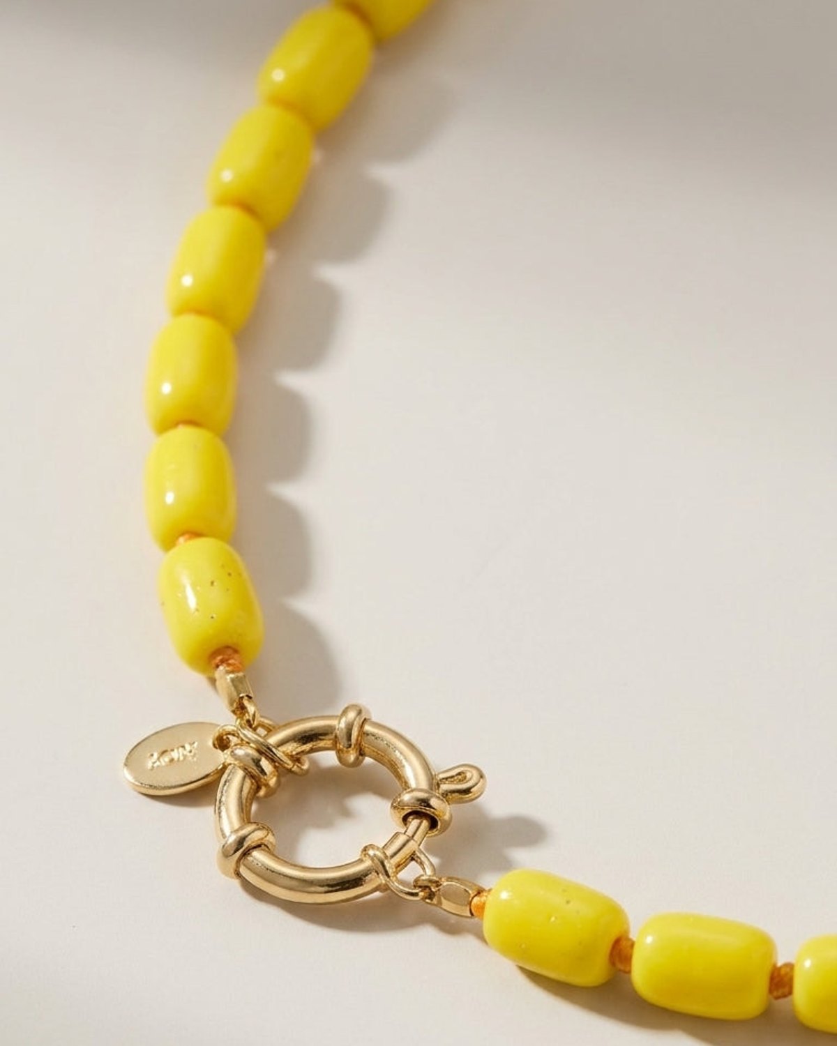 A yellow beaded necklace with chunky barrel-shaped beads and a gold-tone clasp.