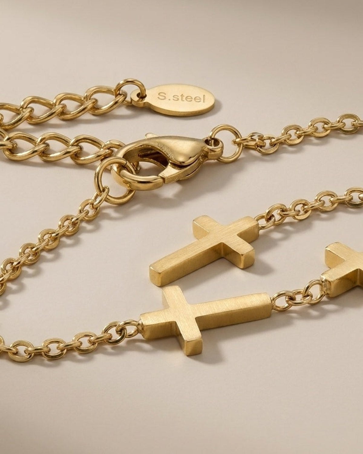 A delicate gold stainless steel chain necklace featuring multiple small cross charms and a lobster clasp.