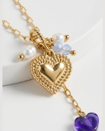 Gold chain necklace featuring a textured heart pendant, pearl and blue beads, and a hanging purple heart drop.