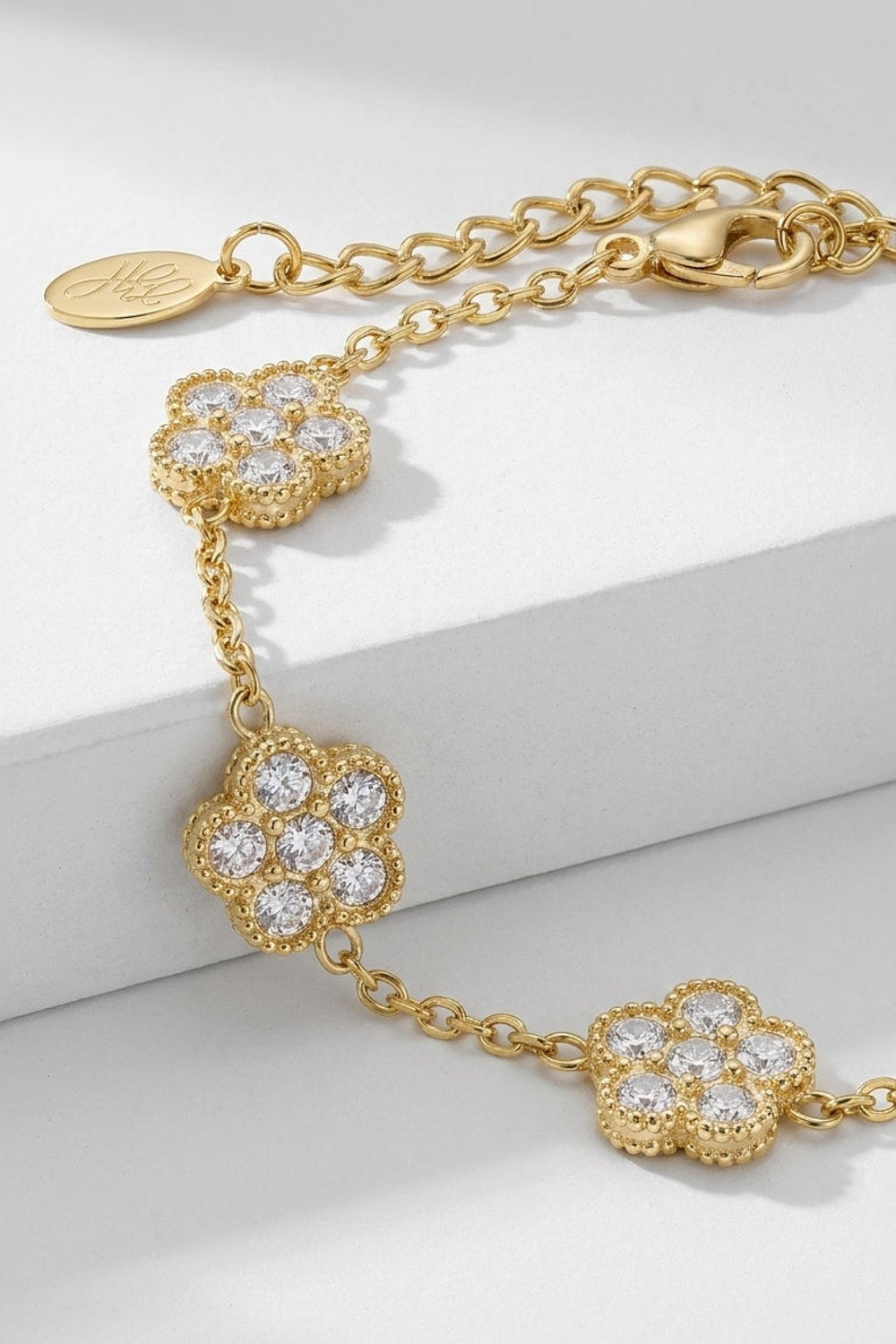 Gold chain Flower Charm Bracelet with crystal-set flower charms and an adjustable link chain.