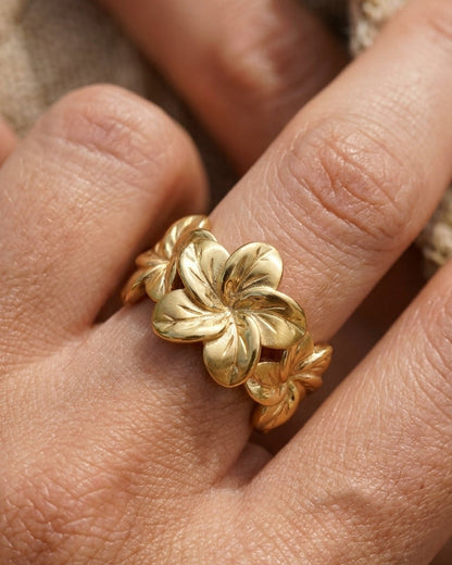 Gold Hibiscus Bloom ring featuring a carved floral design worn on a finger.