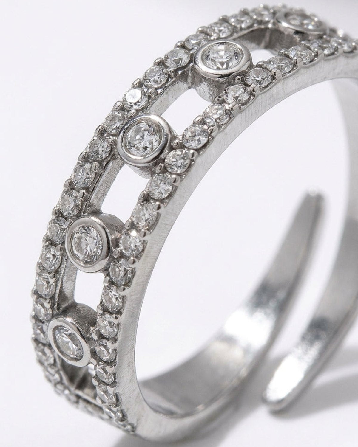 Silver ring with two parallel crystal-pave bands connected by circular bezels holding single round crystals.