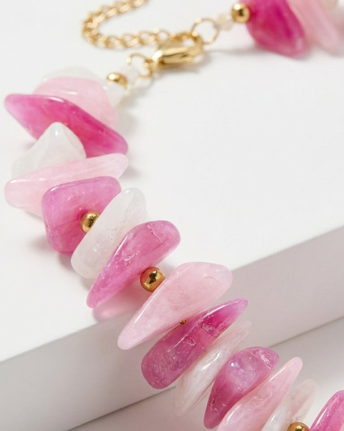 Multi-stone bead necklace with irregular pink, white, and clear stone chips separated by small gold beads.
