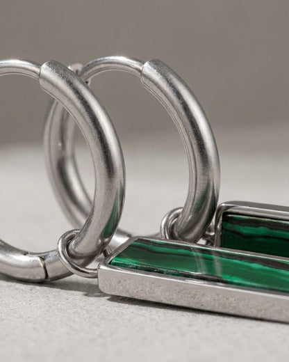Silver hoop earrings with hanging rectangular green gemstone bars featuring banded patterns.
