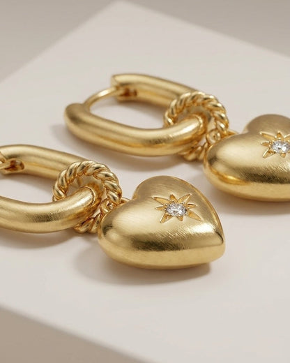 Gold drop earrings with chunky rectangular hoops, twisted rings, and puffy puffy hearts set with a single zircon.