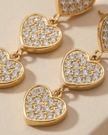 Gold-tone drop earrings featuring three linked pavé-set crystal hearts in graduating sizes.