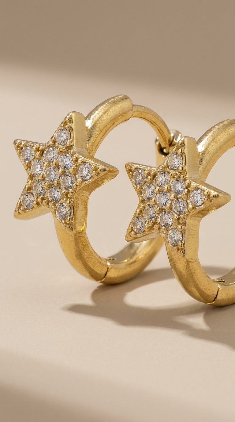 Brushed gold hoop earrings featuring pave-set crystal star charms.