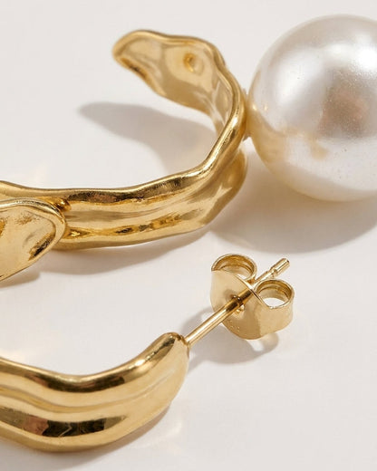 Gold hoop earrings with organic shape and a large white pearl drop.