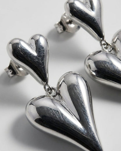 Polished silver-tone drop earrings featuring two puffy heart-shaped charms connected by small rings.