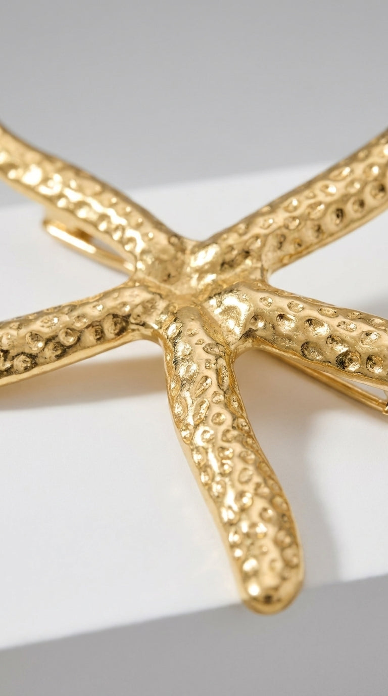 Gold-toned starfish brooch with a textured, pitted surface finish, showcasing a realistic seaside-inspired design.