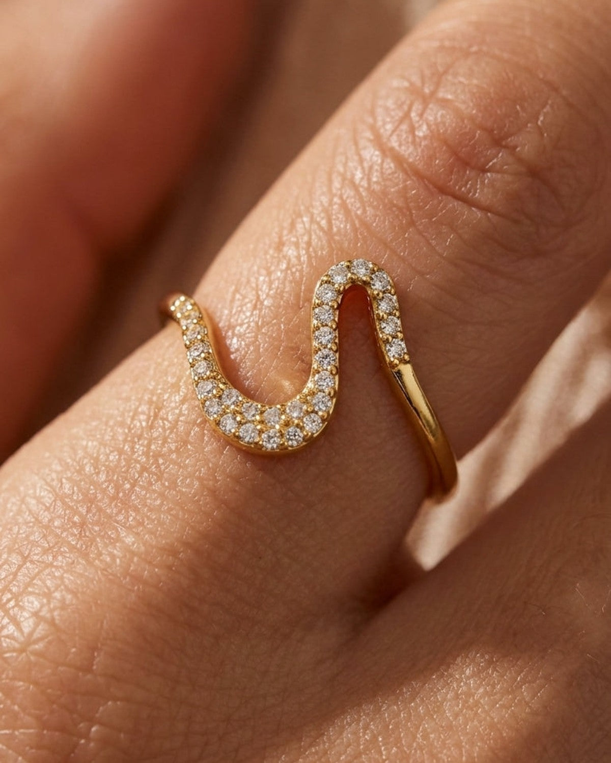 Gold Rhinestone Line Ring with a wavy, serpentine shape on a finger.