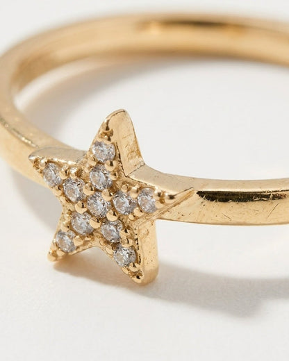 Gold ring featuring a star-shaped setting encrusted with small clear stones on a white background.