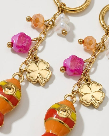 Gold dangle earrings featuring enamel fish, clover charms, pink flowers, and beaded accents.