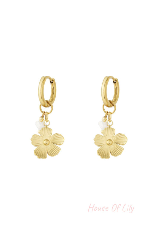 Pair of gold drop earrings featuring textured flower charms with small white bead accents on hoop backs displayed on white background