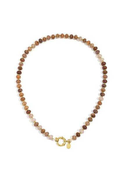 Close-up of a peach and neutral tone stone beaded necklace with gold beads and toggle clasp