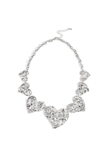 Chunky hammered heart necklace in silver metal with large linked hearts and adjustable chain on white background