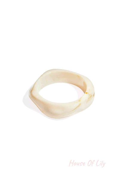 Cream-colored acrylic statement bangle with a smooth, organic, wavy shape and subtle marbled texture.