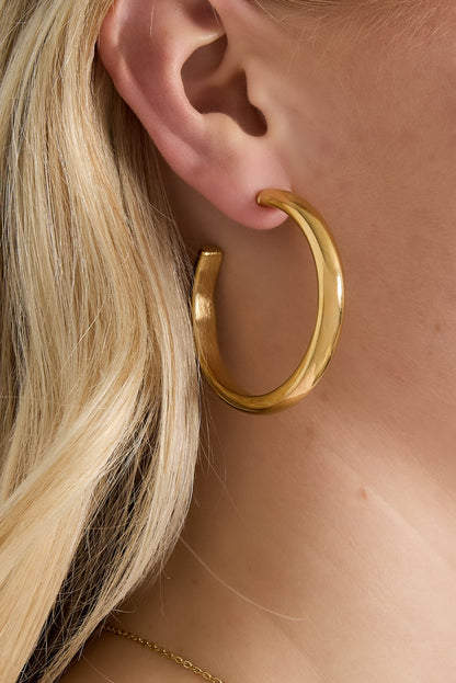 Close-up of gold chunky hoop earring worn by woman with blonde hair